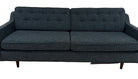 A modern, dark blue fabric sofa with button-tufted back cushions, two seats, and wooden legs, positioned on a light carpet against a plain wall.