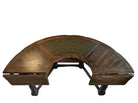 A curved wooden desk with a green leather inlay, featuring intricate detailing and storage drawers, set on a hardwood floor against a light wall.