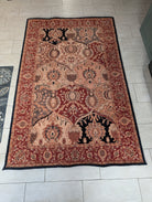 A decorative area rug features intricate floral patterns in warm reds, golds, and blacks, placed on a light tiled floor.