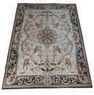 An overhead view of a decorative rug with floral patterns, placed on a tiled kitchen floor. A pair of feet in socks is visible at the bottom.