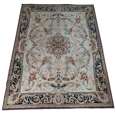 An overhead view of a decorative rug with floral patterns, placed on a tiled kitchen floor. A pair of feet in socks is visible at the bottom.