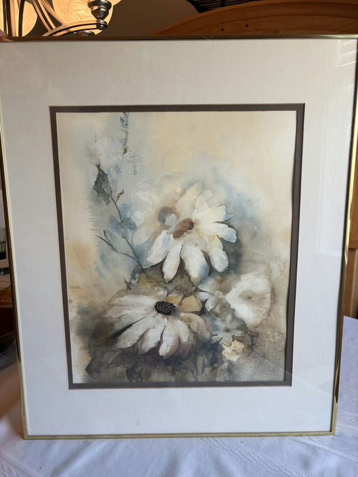A framed watercolor painting of white daisies with soft blue and beige hues, featuring delicate brush strokes and a serene background.