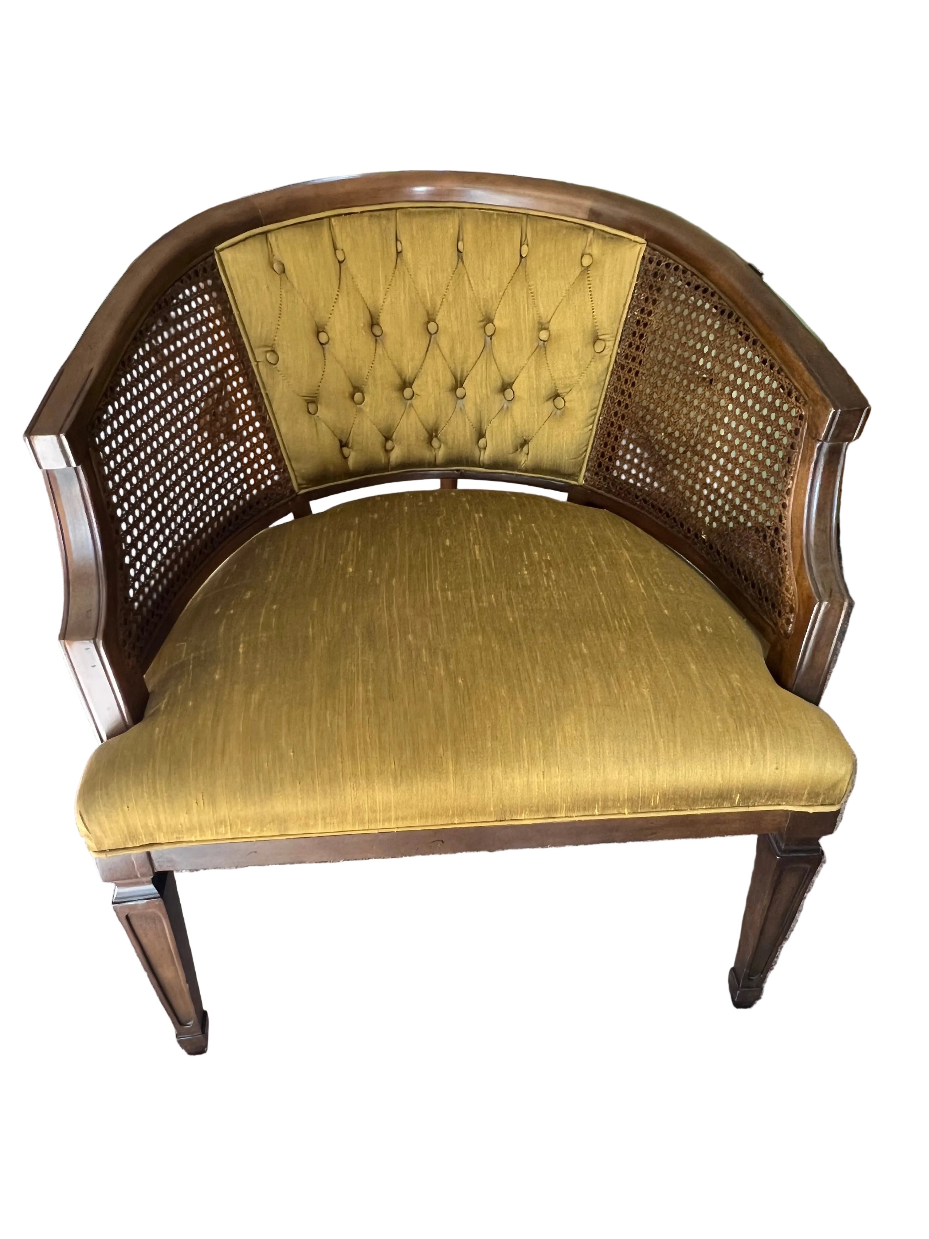 A vintage half-moon chair with a tufted mustard-yellow fabric seat and cane backrest, set on a light carpet, surrounded by household items.