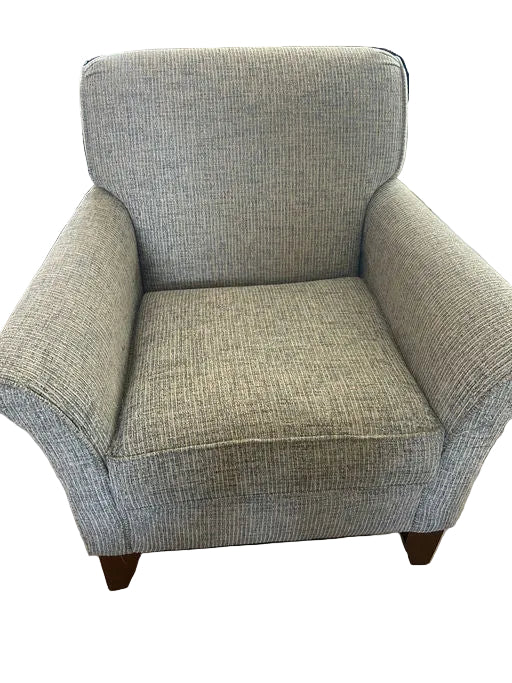 A gray and cream accent chair with rounded edges and wooden legs is displayed on a hardwood floor, with a stroller partially visible in the background.