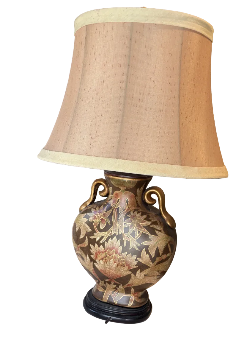 A decorative lamp features an ornate floral design on the base, complemented by a beige lampshade. The lamp sits on a circular table.