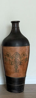 Three decorative vases displayed on a wooden floor, featuring intricate designs with copper and black finishes against a light wall.