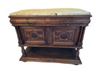 A wooden sideboard with ornate carvings and a marble top, featuring two cabinets with decorative doors and elaborate hardware, stands on a tiled floor.
