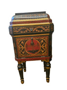 A vintage decorative nightstand with intricate floral patterns, featuring a red and black color scheme, and ornate gold detailing, stands on four legs.