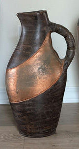 Three decorative vases in varying heights, with a mix of dark and copper tones, showcasing ornate designs and patterns, set against a neutral wall.