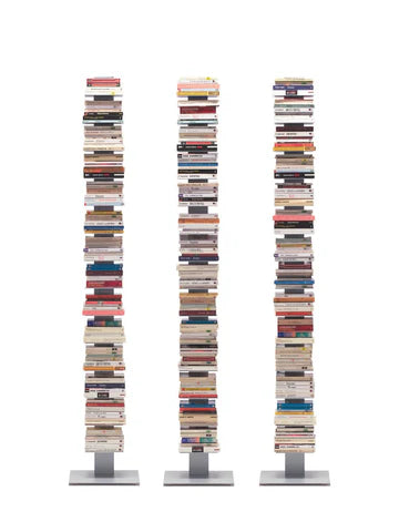 Three tall book stacks are arranged on sleek bases, each filled with a variety of colorful book covers and spines, creating a visually striking display.