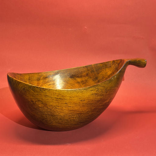 A beautifully crafted wooden bowl with a smooth, polished finish and a unique curved shape, set against a vibrant red background.