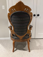 A vintage wooden chair with an ornate backrest and patterned upholstery sits on a light carpet, facing a pair of closed white doors.
