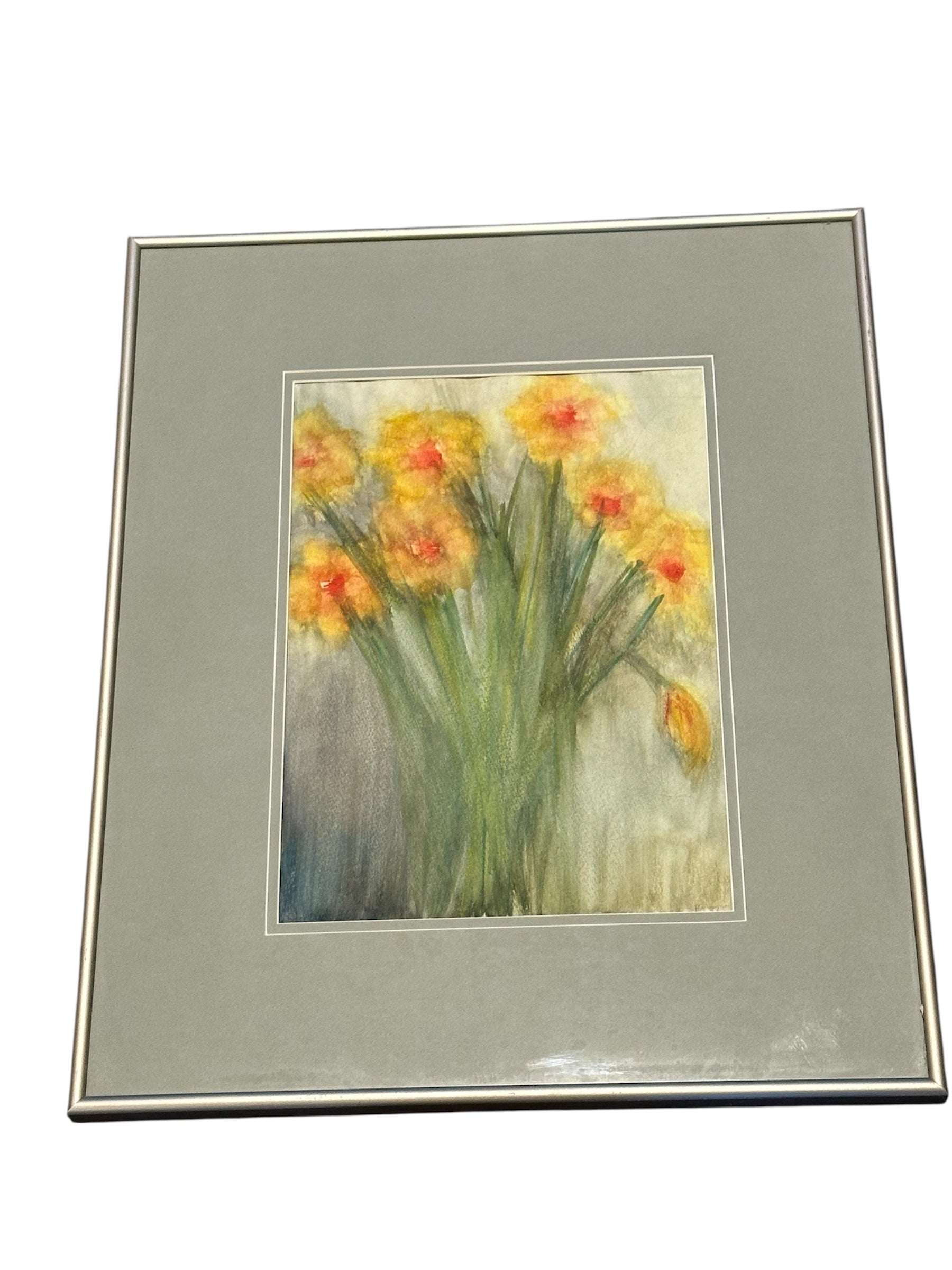 A framed artwork featuring a vibrant bouquet of yellow flowers with hints of orange, set against a soft, muted background.