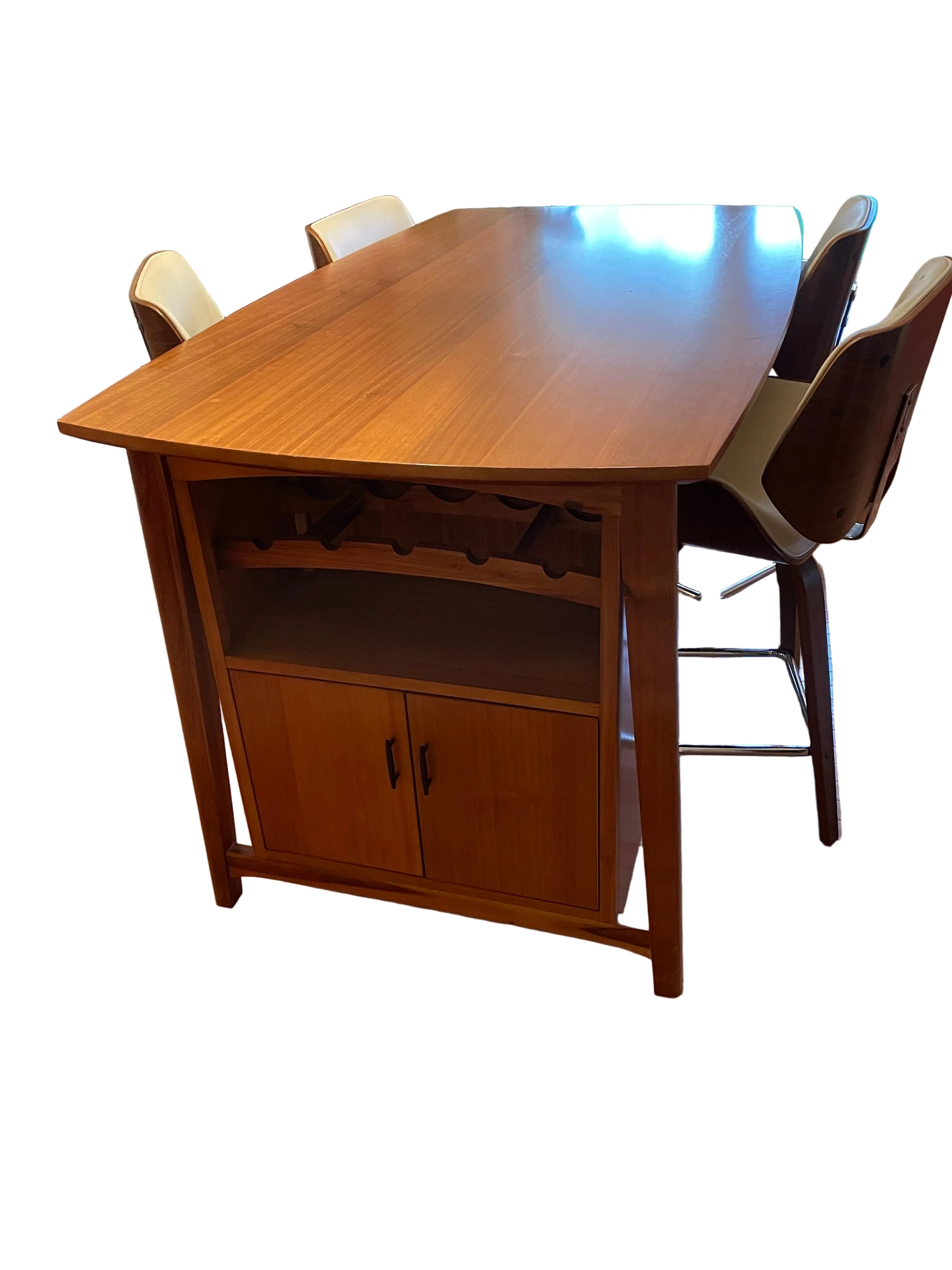 A wooden dining table with a glossy finish and storage cabinet underneath, flanked by two modern chairs, set in a well-lit room with plants.