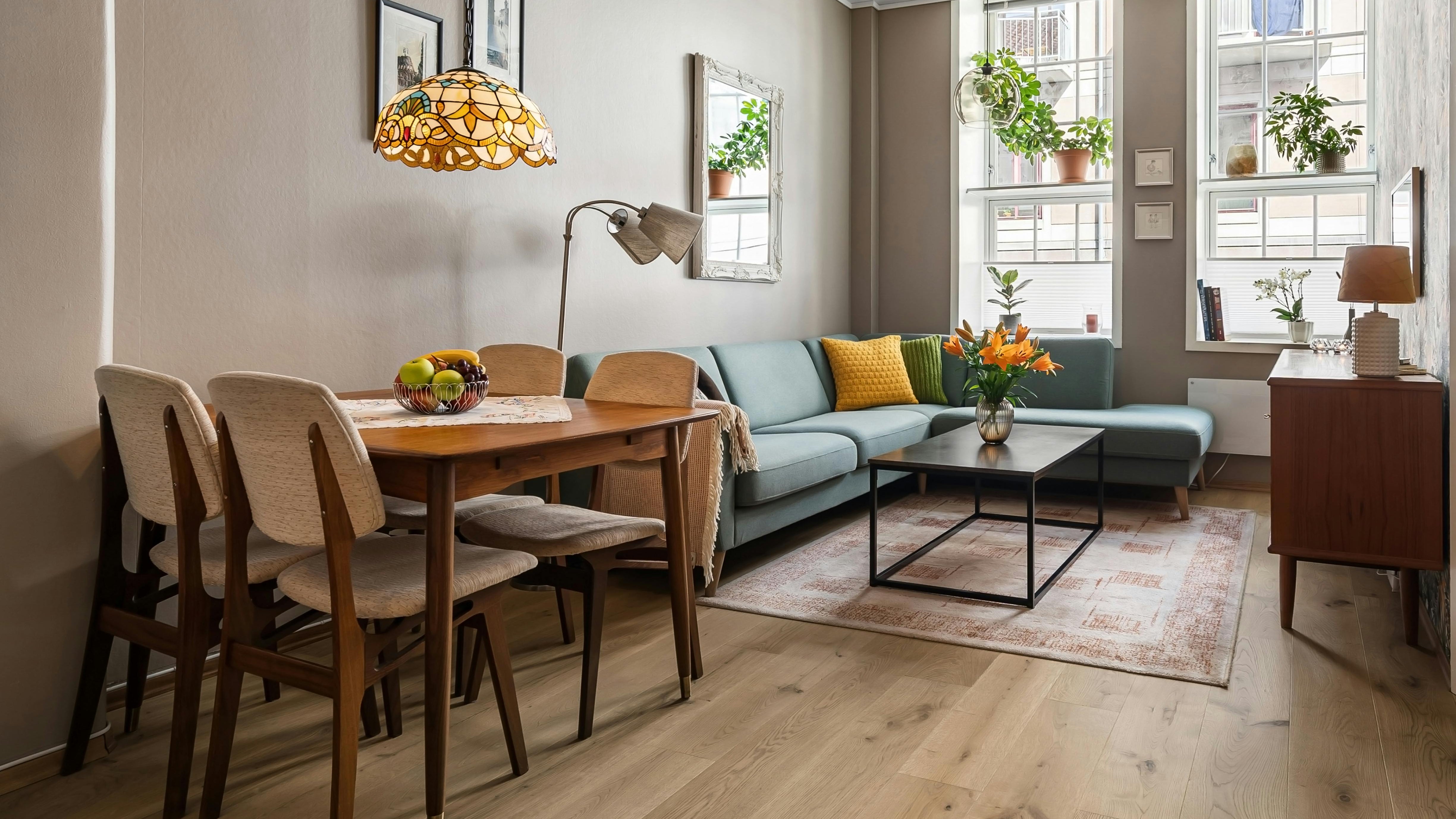 Stylish living room with dining area, wooden furniture, and indoor plants, creating a cozy atmosphere.