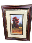 A framed painting features vibrant autumn trees in shades of red and orange, set against a soft blue sky and distant fields.
