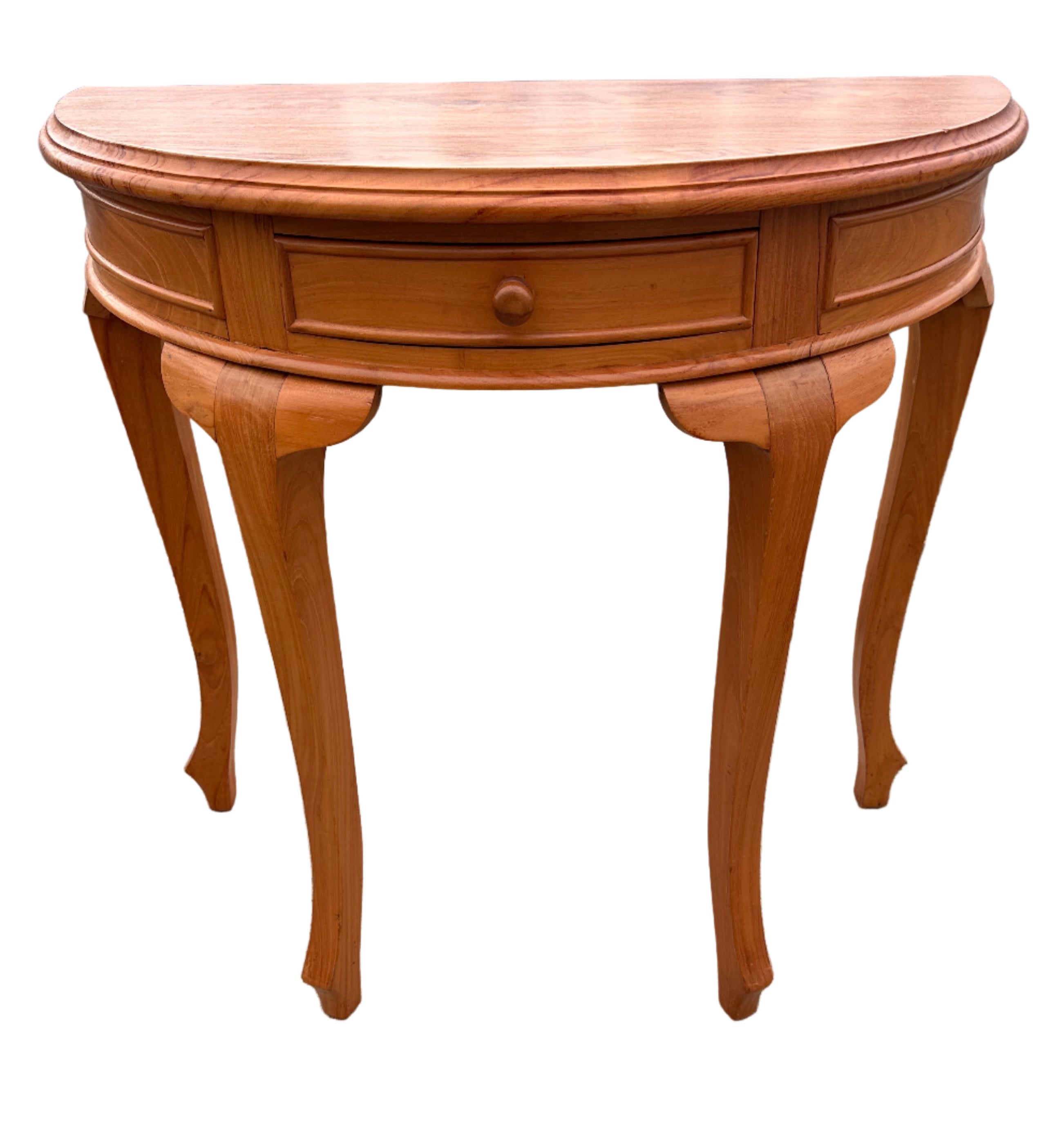 A curved, wooden console table with one drawer and elegant, tapered legs, placed on concrete near a gray corrugated backdrop.