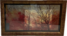 Framed artwork featuring silhouetted trees against a warm, gradient background of reds and yellows, evoking a serene sunset atmosphere.