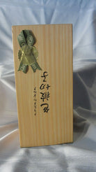 A wooden box with a ribbon and tag labeled "Glass Café" features stylized text in an Asian script, set against a smooth, light fabric backdrop.